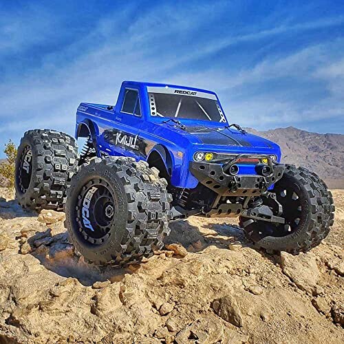 Blue RC monster truck on rocky terrain with blue sky.