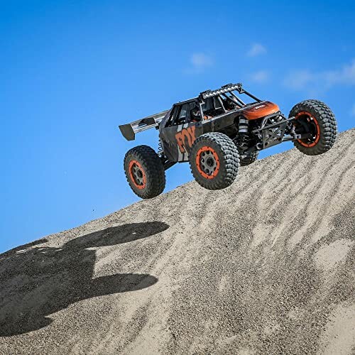 RC car jumping over a sand dune against a blue sky