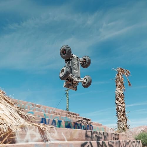 Remote control car performing a jump over graffiti-covered stairs.